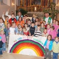Viele Kinder mit Pfarrer beim Gottesdienst