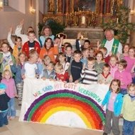 Viele Kinder mit Pfarrer beim Gottesdienst
