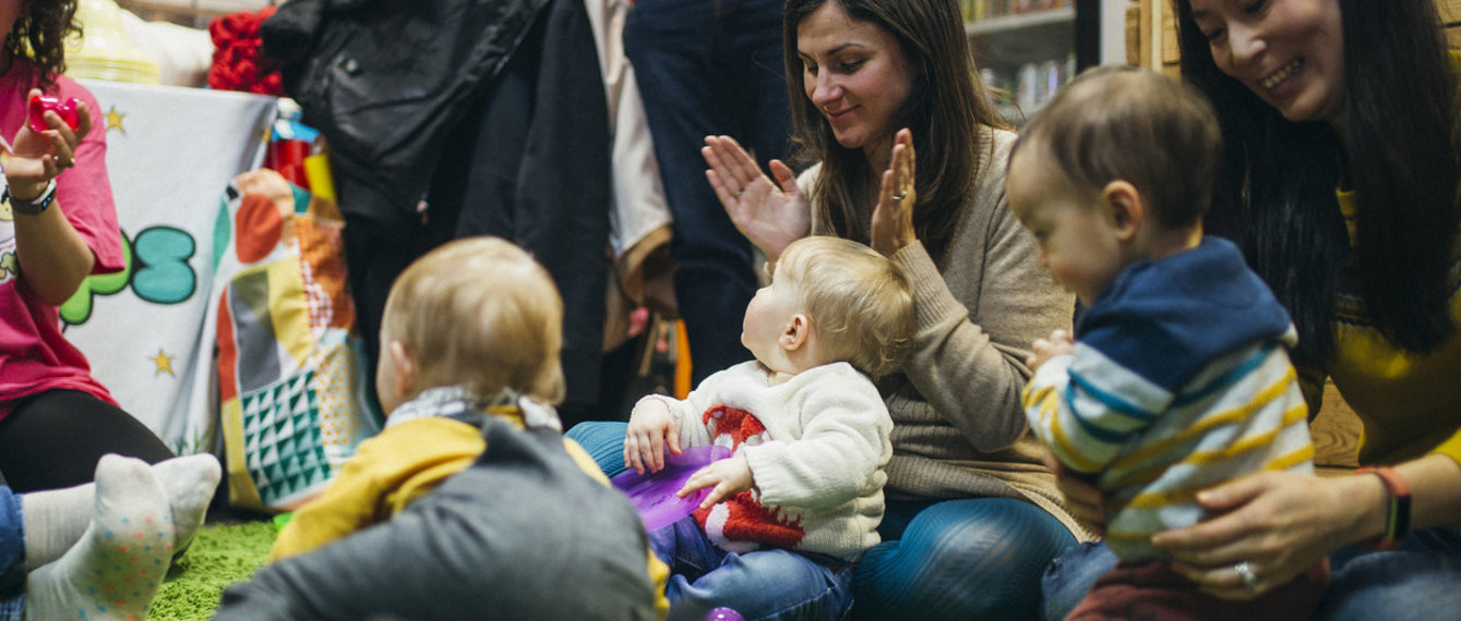 Mütter sitzen mit ihren Babys am Boden und spielen