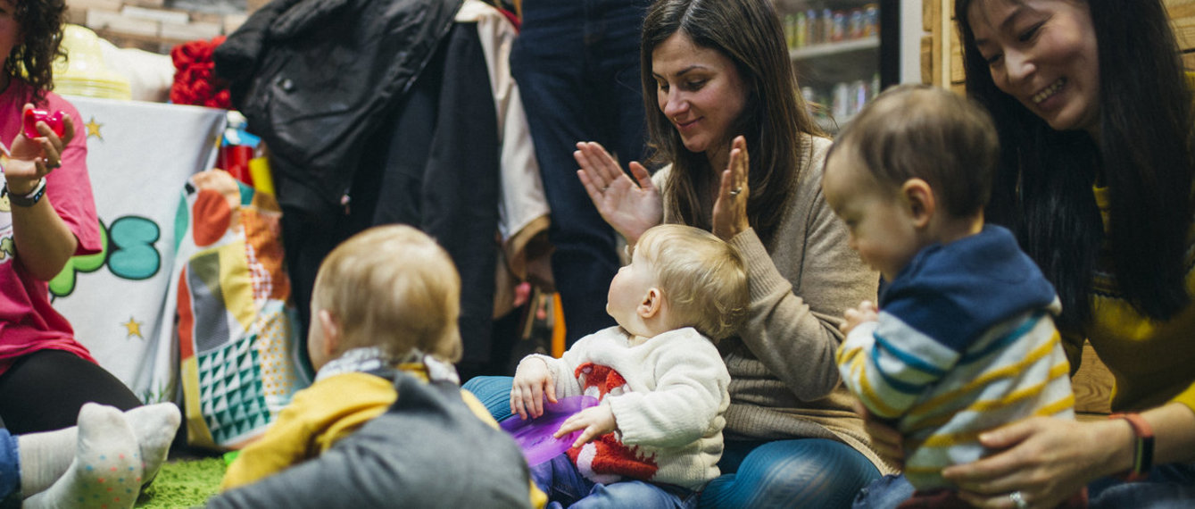 Mütter sitzen mit ihren Babys am Boden und spielen