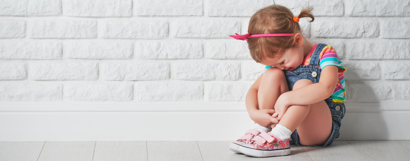 Emotionale Kompetenzen von Kleinkindern stärken - meinefamilie.at Trauriges Kind sitzt vor Ziegelwand