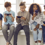 Viele Kinder sitzen und schauen aufs Handy
