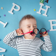 Baby mit Brille umgeben von Buchstaben