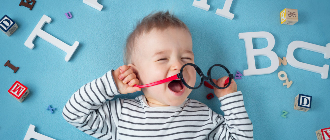 Baby mit Brille umgeben von Buchstaben