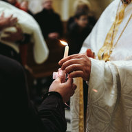 Pfarrer mit Taufkerze