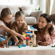 Kindliche Förderung: Wie und ab wann soll ich mein Kind fördern?  © iStock Mutter liegt mit Kindern am Teppich spielt mit Bausteinen