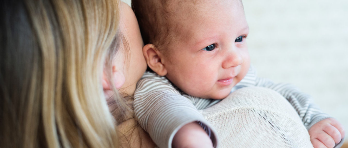 Baby wird von Mutter im Arm gehalten