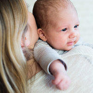 Baby wird von Mutter im Arm gehalten