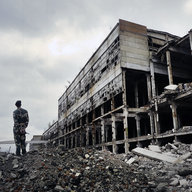 Soldat steht vor Ruine