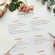 Hände füllen Hochzeitsplanung auf Papier aus, Handy liegt daneben