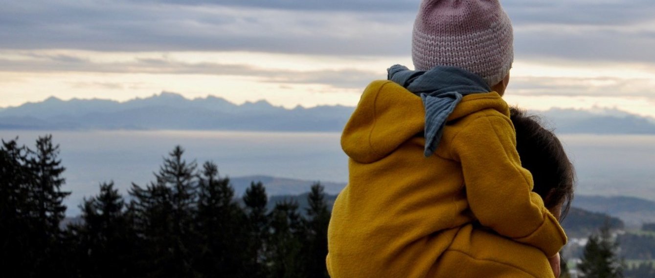 kind im overall sitzt auf den schultern der mutter in einer herbststimmung