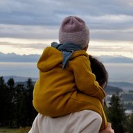 kind im overall sitzt auf den schultern der mutter in einer herbststimmung