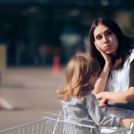Frau lehnt deprimiert am Einkaufswagen