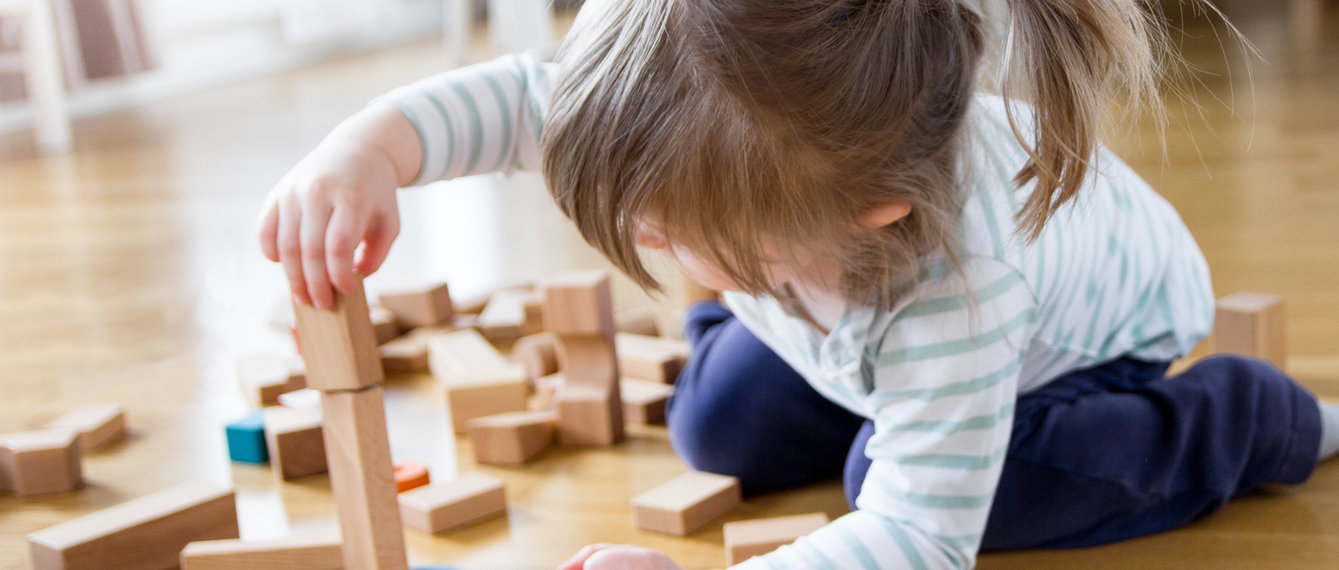 Kleines Mädchen spielt mit Holzbausteinen