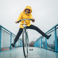 Frau fährt mit Rad im Regen mit gelben Regenmantel