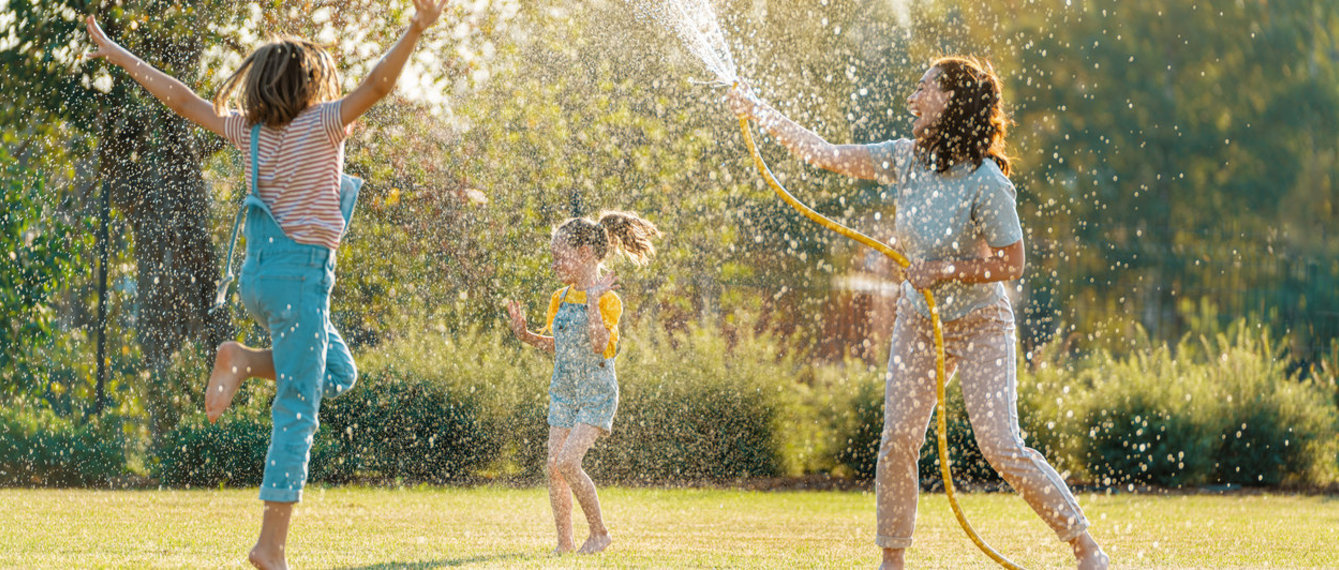 Kinder und Mutter pritscheln im Garten