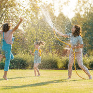 Kinder und Mutter pritscheln im Garten