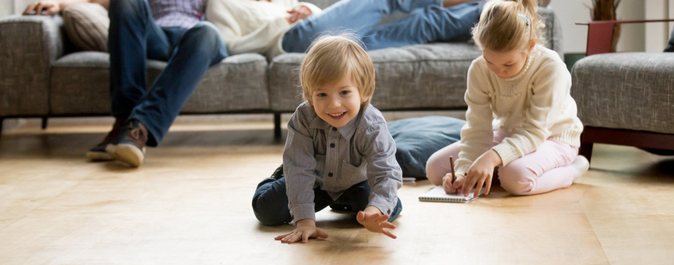 Eltern sitzen auf der Couch und die Kinder spielen am Boden