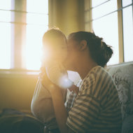 Mutter küsst Baby auf die Wange