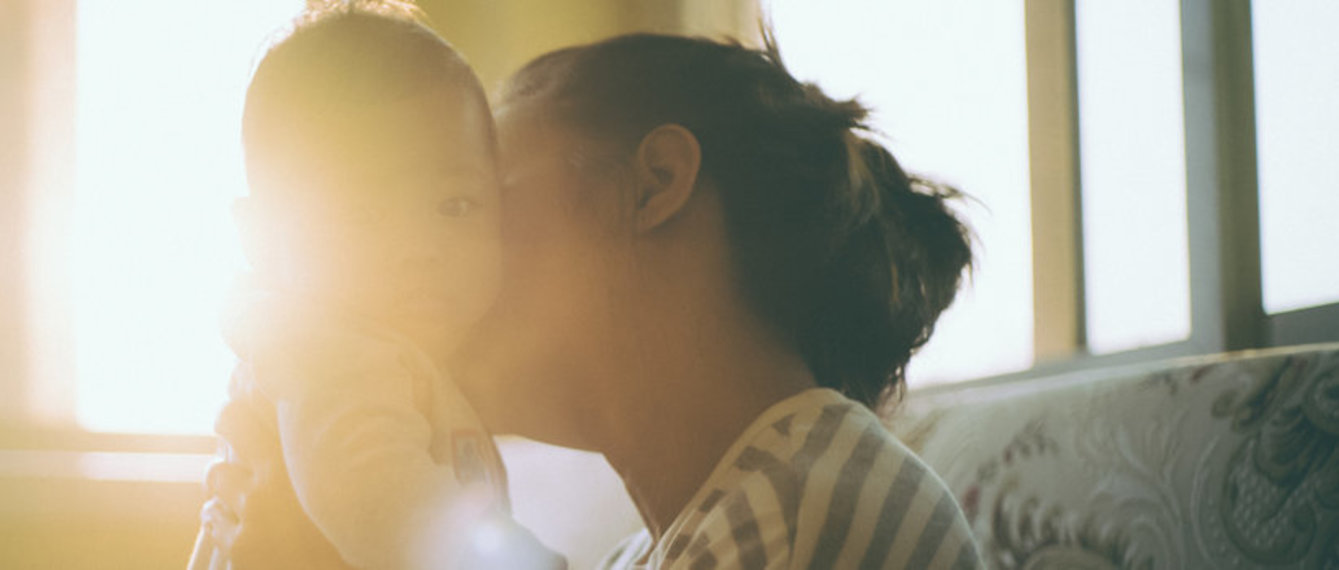 Mutter küsst Baby auf die Wange