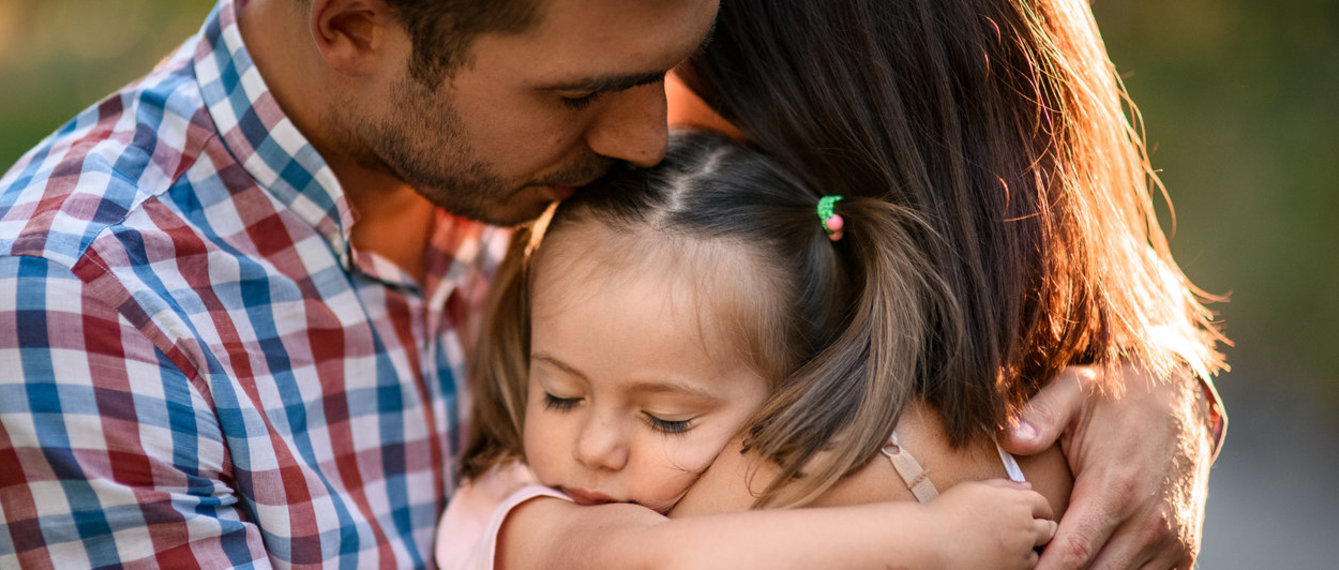 Eltern umarmen ihre Tochter