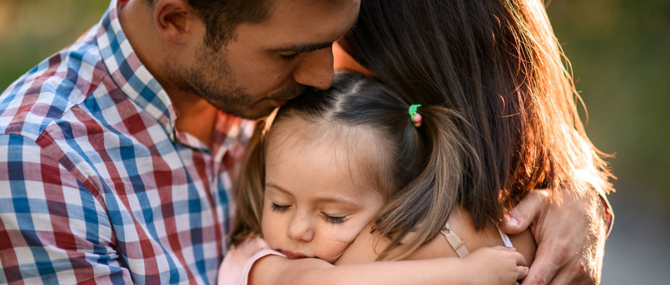 Eltern umarmen ihre Tochter