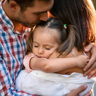 Eltern umarmen ihre Tochter