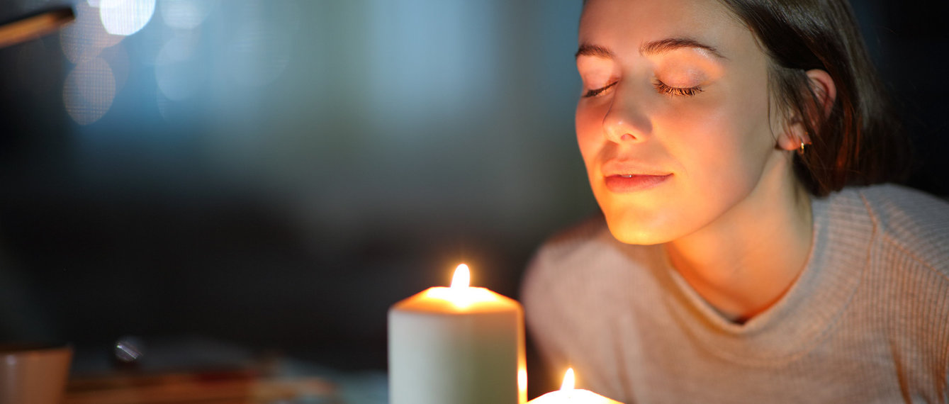 Frau riecht an Kerze bei Nacht