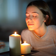 Frau riecht an Kerze bei Nacht