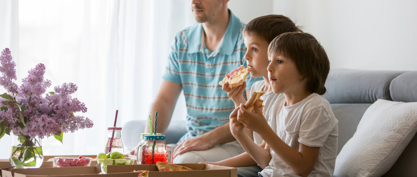Kinder und Vater essen vor Fernseher