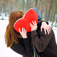 Paar küsst sich hinter einem Stoffherz