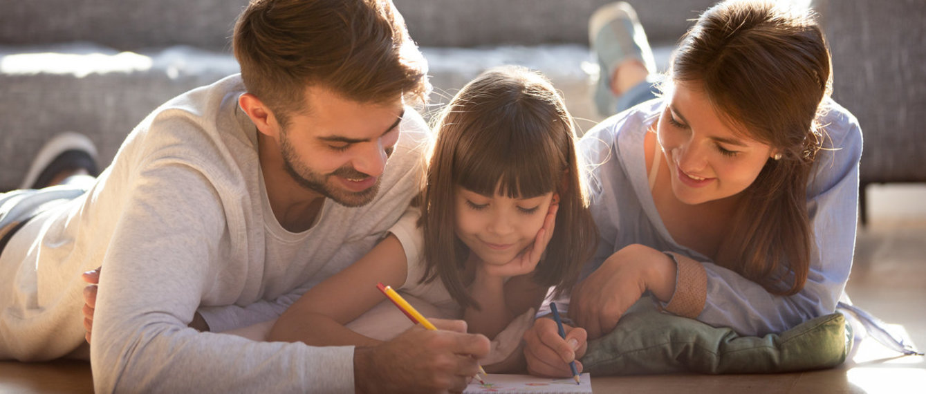 Familie liegt am Boden und zeichnet