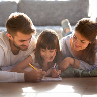 Familie liegt am Boden und zeichnet