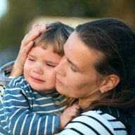 Kleinkind weint auf Arm der Mutter