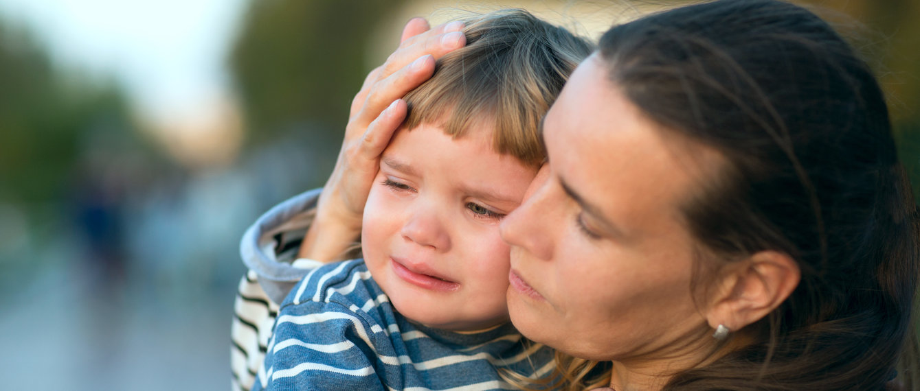 Kleinkind weint auf Arm der Mutter