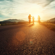 Vater fährt mit Kindern bei Sonnenuntergang Rad