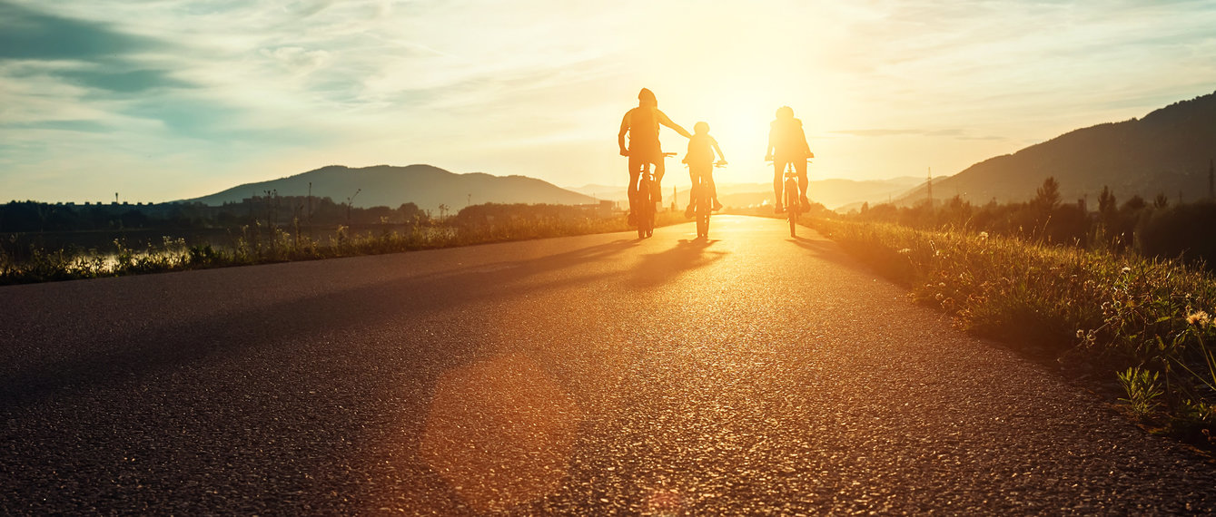 Vater fährt mit Kindern bei Sonnenuntergang Rad