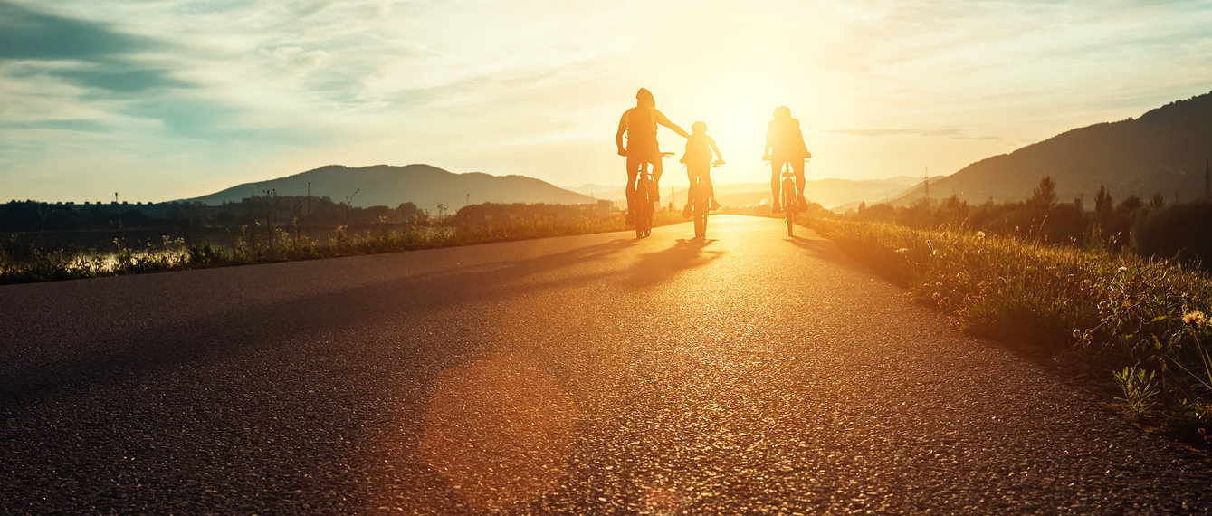 Vater fährt mit Kindern bei Sonnenuntergang Rad