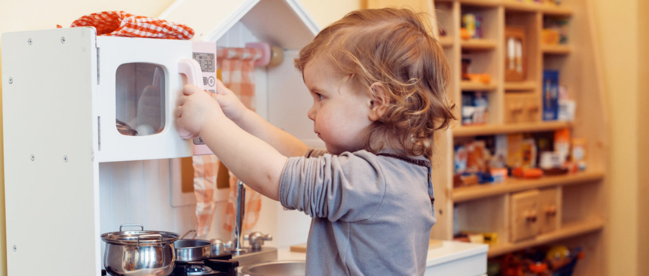 kid playing with toy kitchen