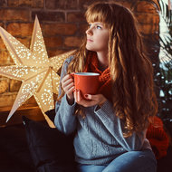 Frau trinkt in Ruhe Tee vor einem Weihnachtsstern