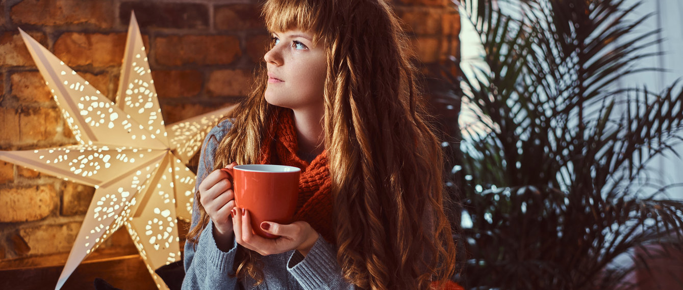 Frau trinkt in Ruhe Tee vor einem Weihnachtsstern