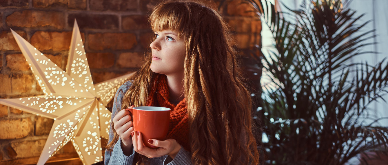 Frau trinkt in Ruhe Tee vor einem Weihnachtsstern