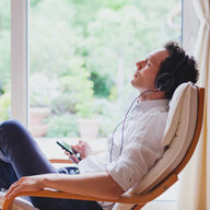 Mann sitzt alleine im Wohnzimmer und hört Musik