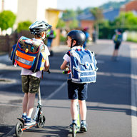 Kinder fahren mit Roller in die Schule