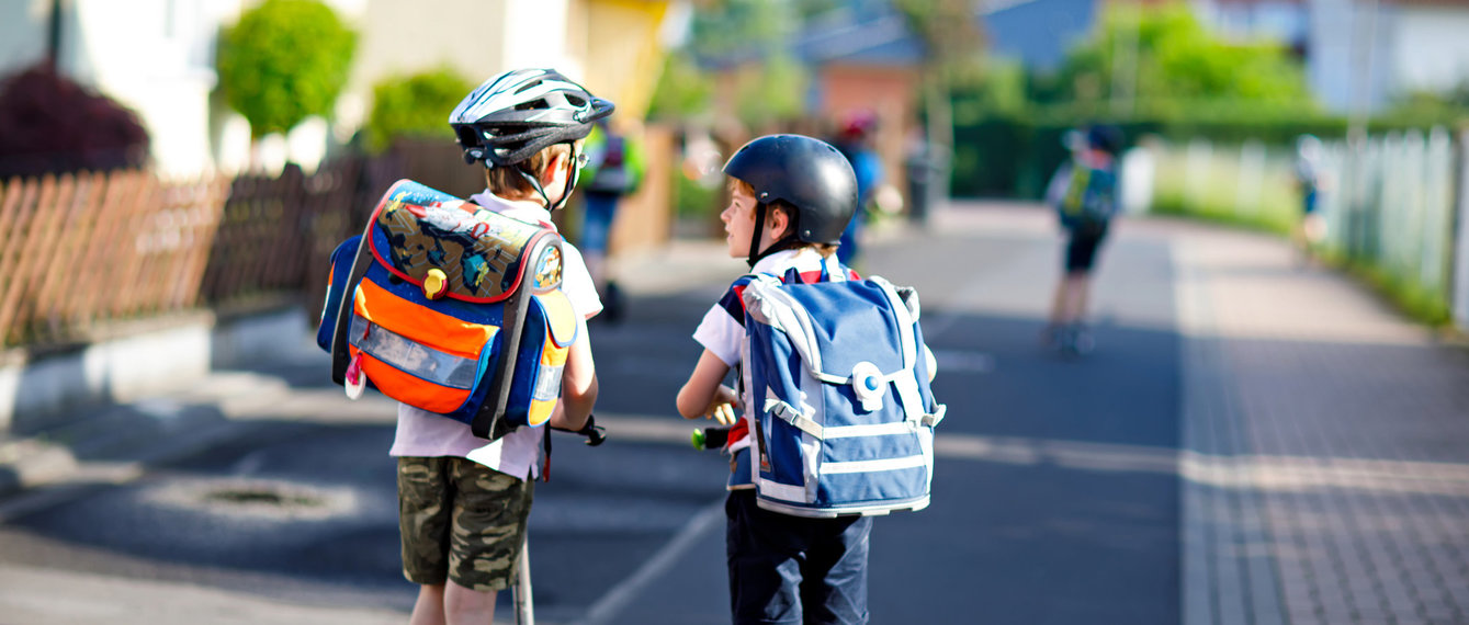 Kinder fahren mit Roller in die Schule