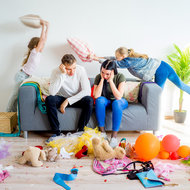 Überforderte Eltern inmittem des Chaos, dass ihre Kinder gerade anrichten.