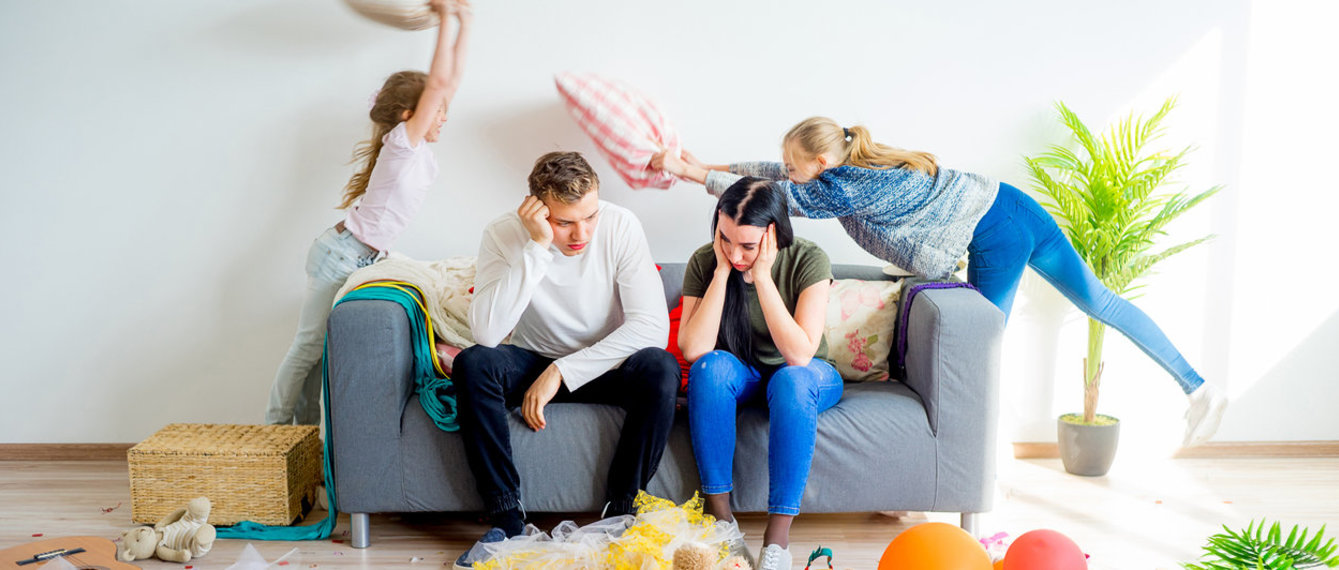 iStock/ElenaNichizhenova Überforderte Eltern inmittem des Chaos, dass ihre Kinder gerade anrichten.