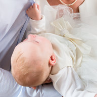 Vater und Mutter halten das Taufkind im weißen Taufkleid