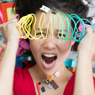 Überforderte Mutter mit Spielzeug rundherum