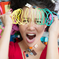 Überforderte Mutter mit Spielzeug rundherum